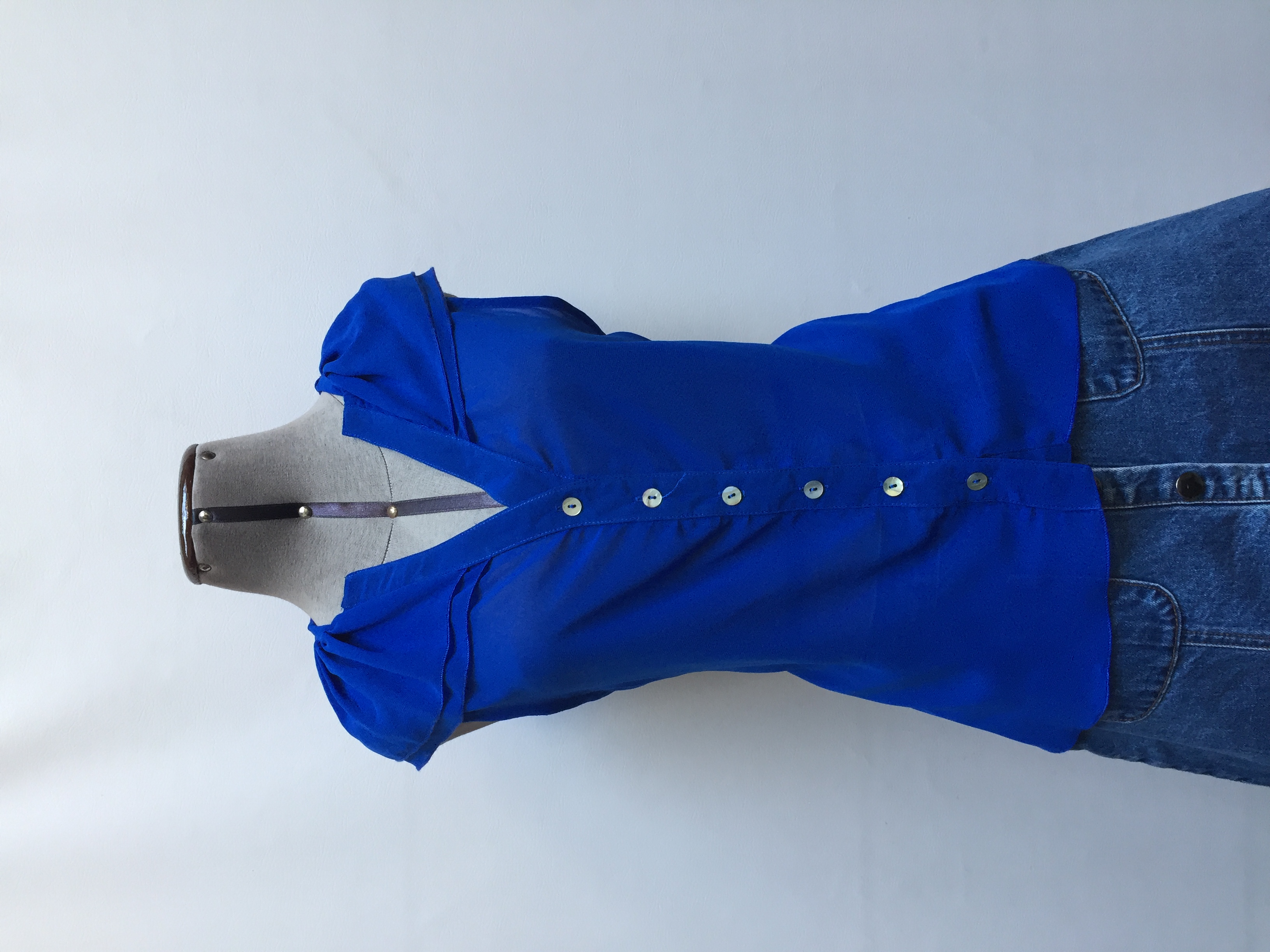 Blusa de gasa azul con volante en el cuello, botones delanteros y basta asimétrica. Busto 102cm Largo 50-80cm