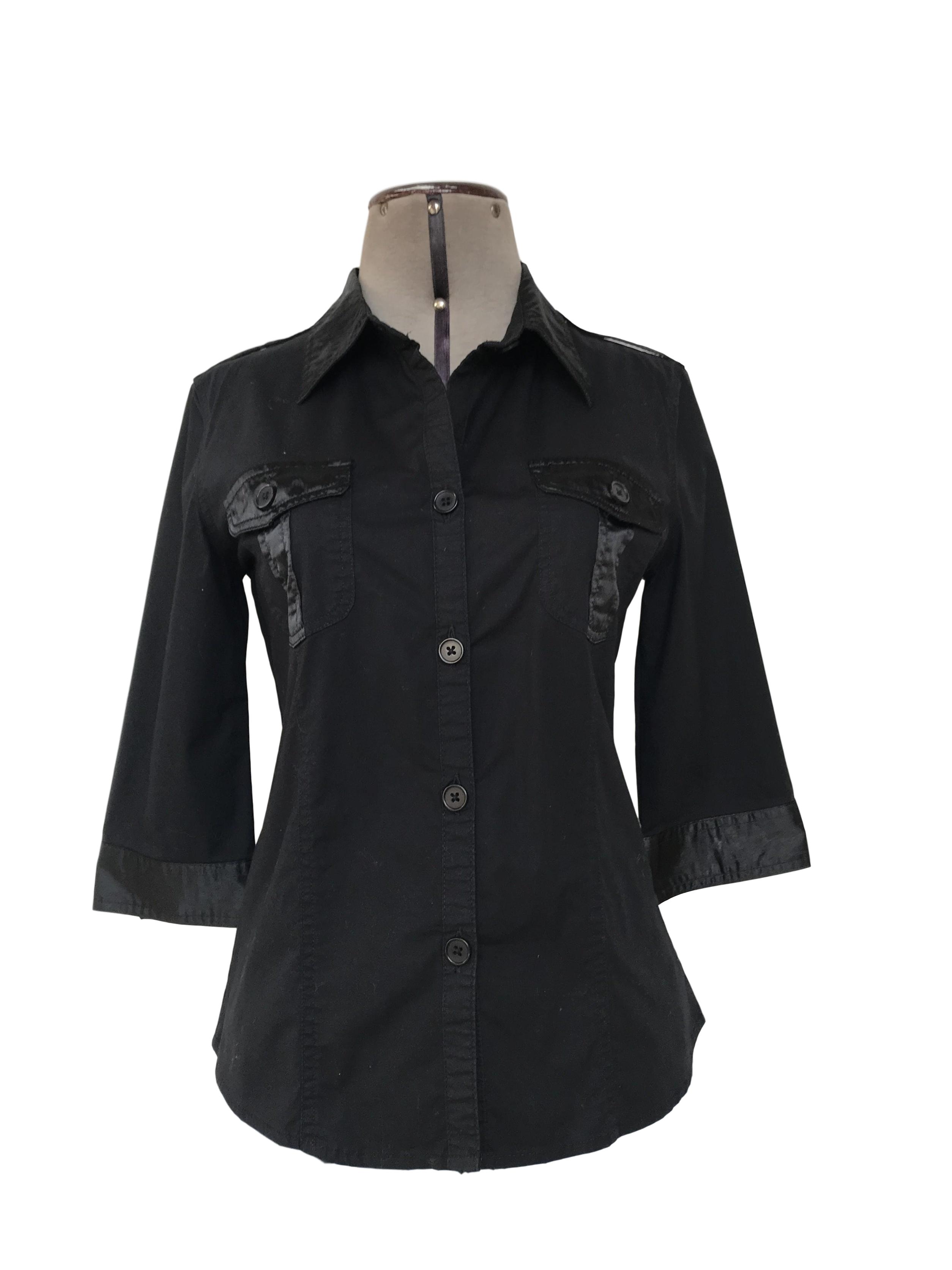 Blusa 96% algodón negro con aplicaciones de tela satinada, cuello camisero, manga 3/4 bolsillos parche en el pecho y botones al tono.Talla S