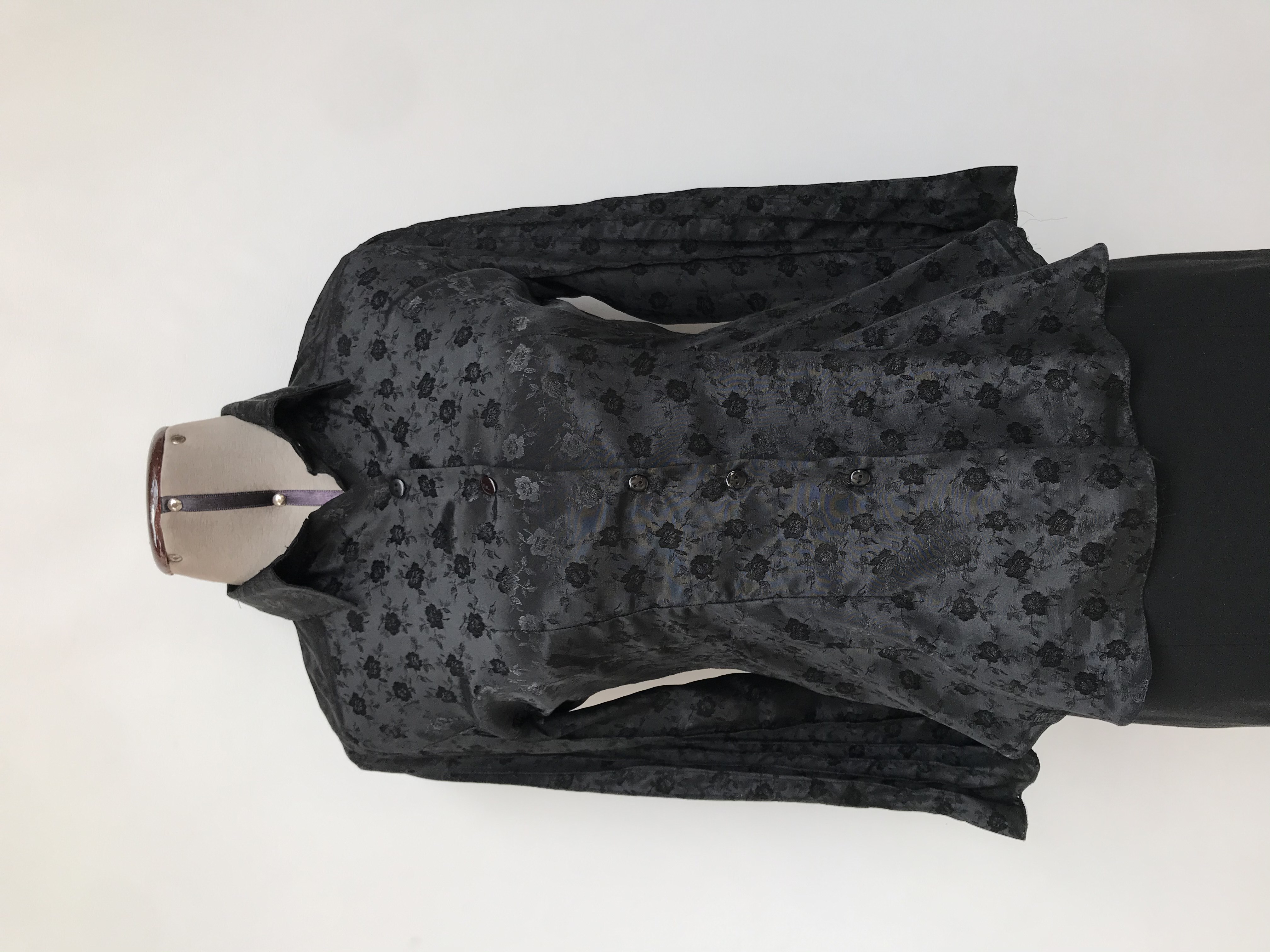 Blusa negra con brocado de flores al tono, camisera con botones, pinzas y costuras en relieve en mangas
Talla S