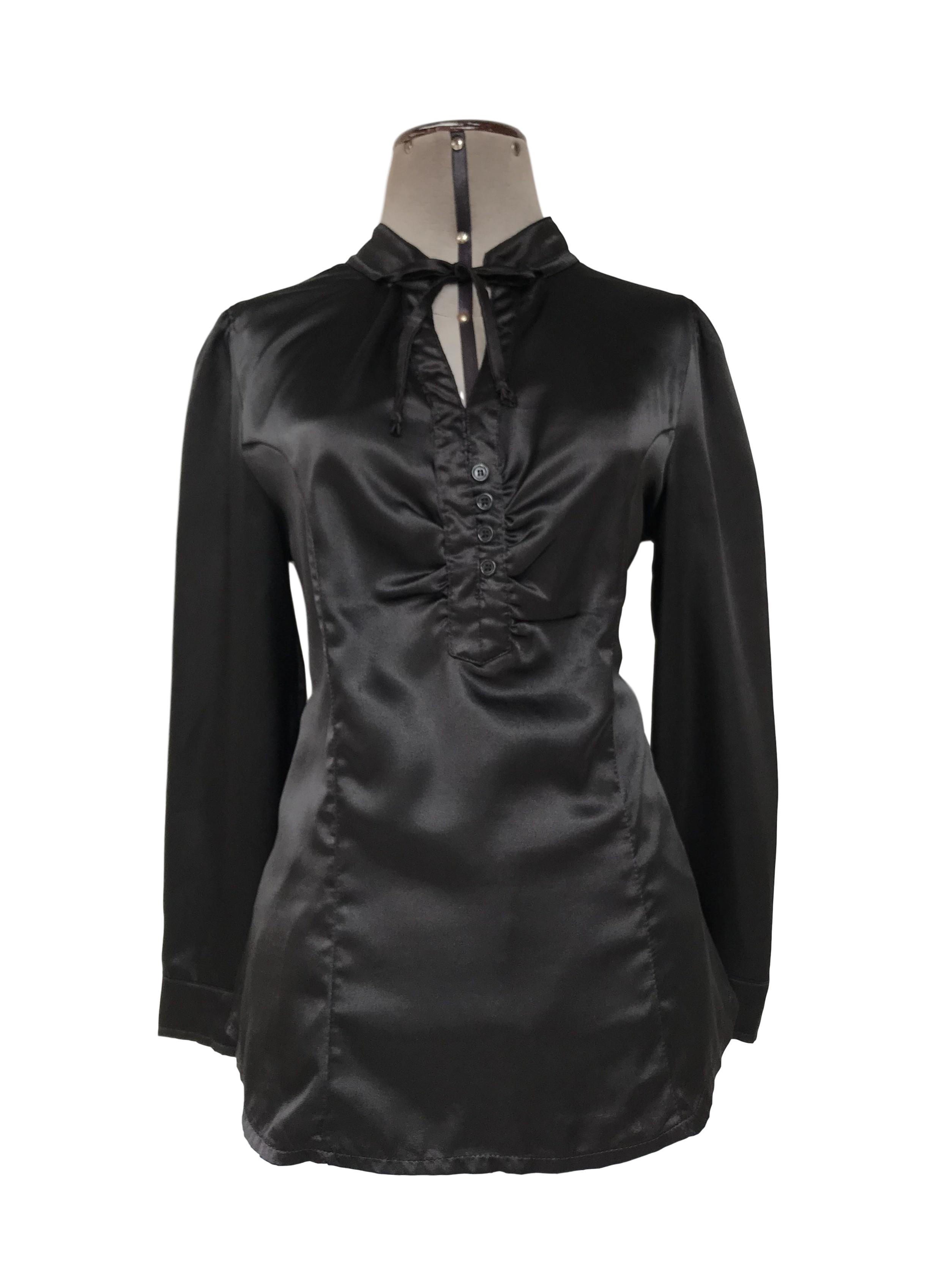 Blusa negra satinada, cuello nerú con tiras para amarrar, escote en V y botones negros, tiene pinzas delanteras y traseras
Talla M