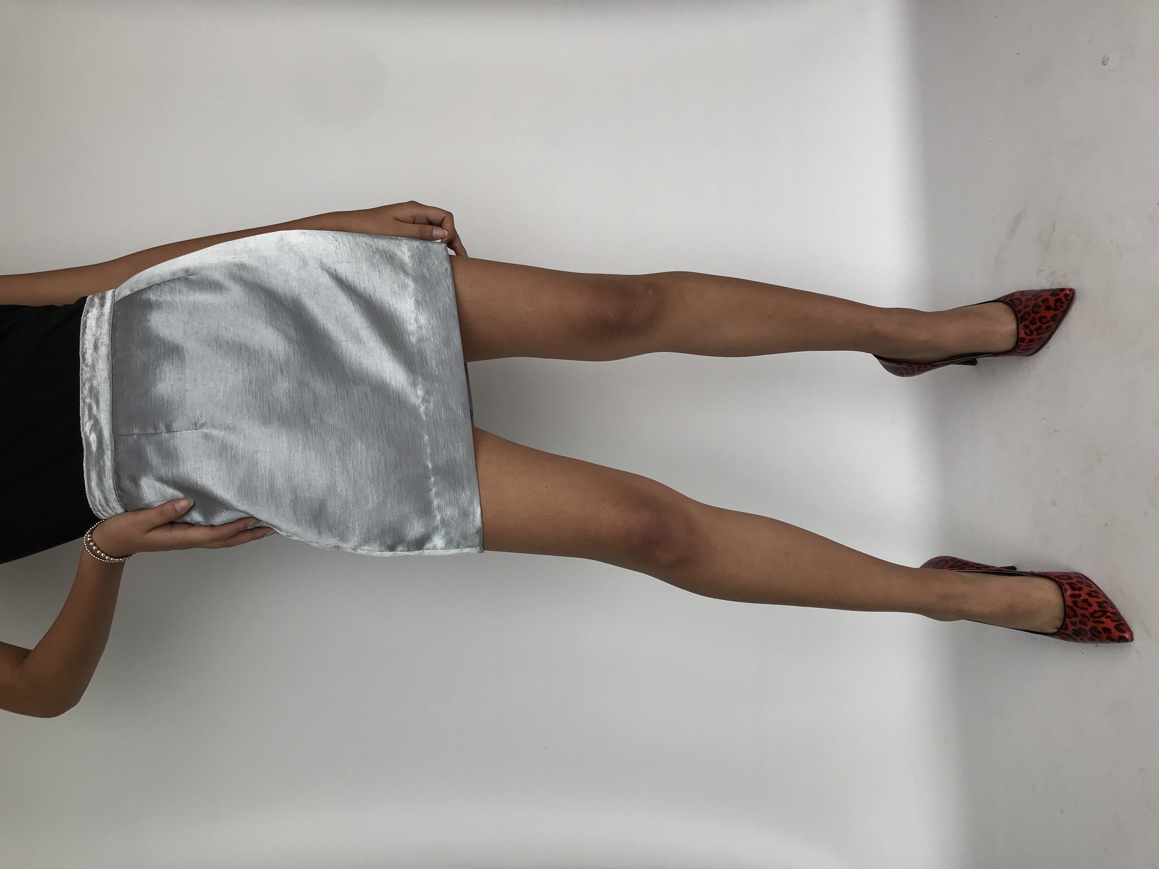 Falda mini plateada satinada con cierte y botón posterior. Cintura 75cm