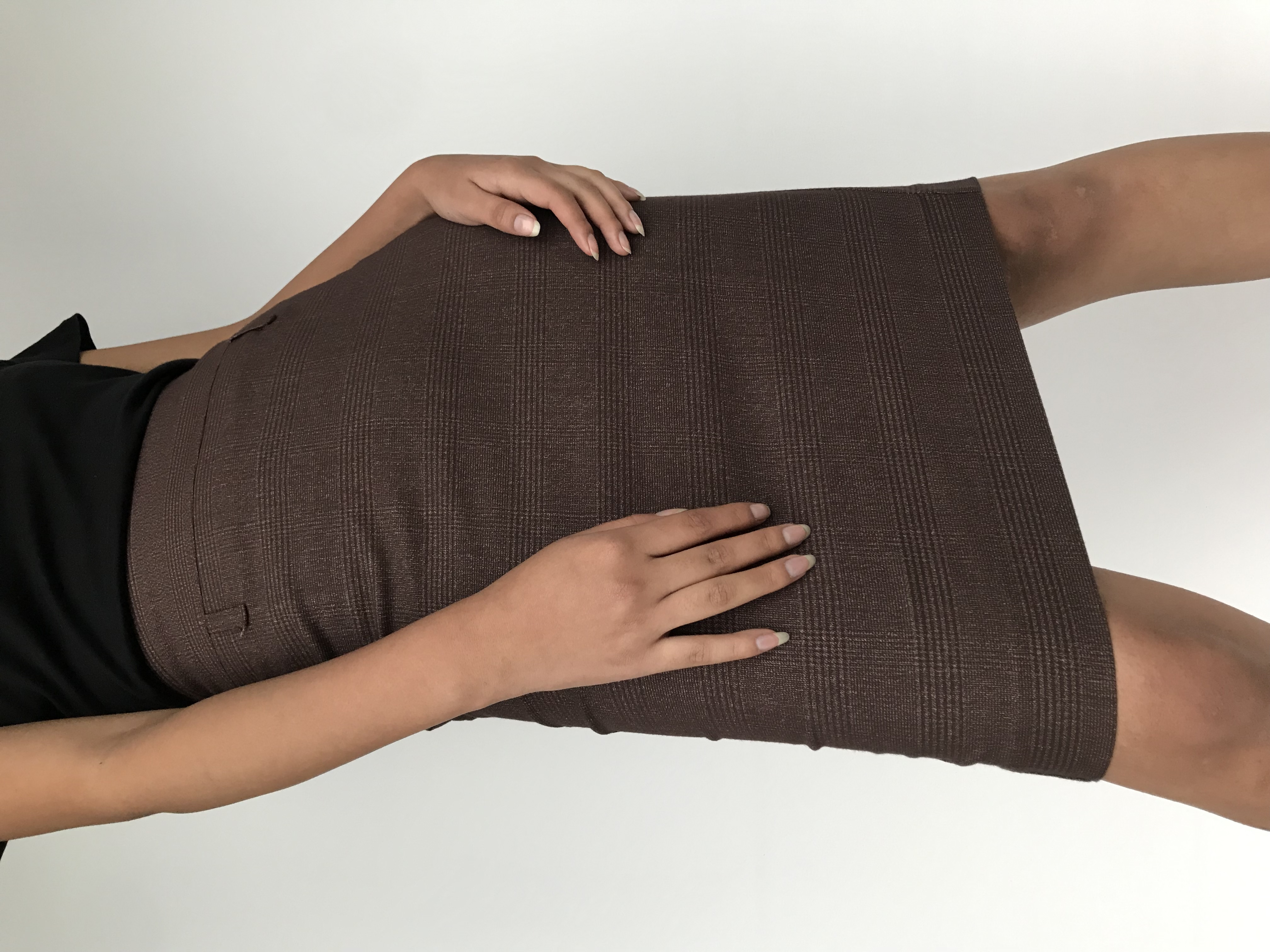 Falda marrón con líneas cruzadas al tono, pretina ancha, cierre posterior y abertura en la basta
Talla S
