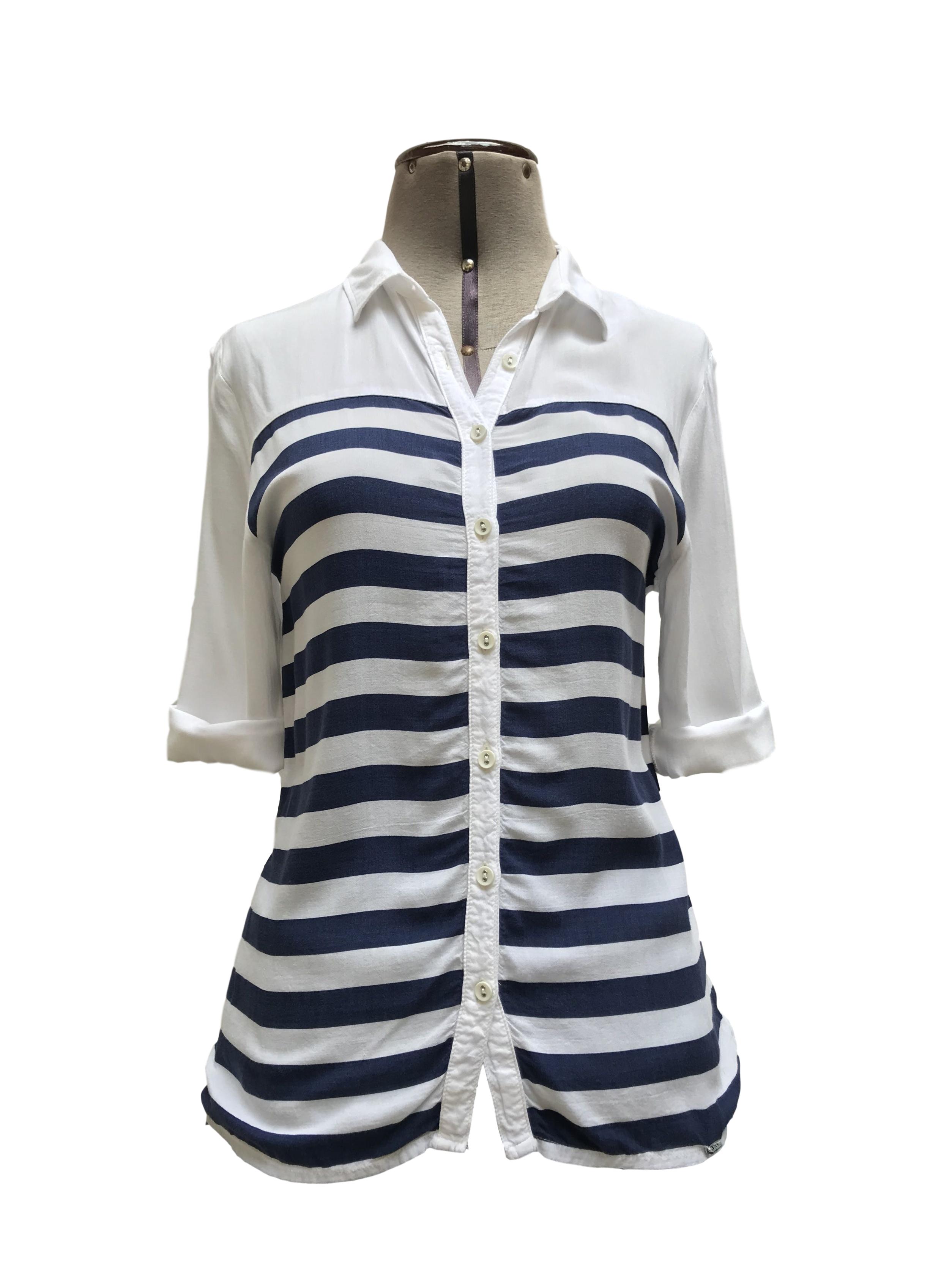 Blusa Exit blanca con estampado de franjas azules horizontales, cuello camisero y fila de botones, manga 3/4 regulable con botón
Talla XS