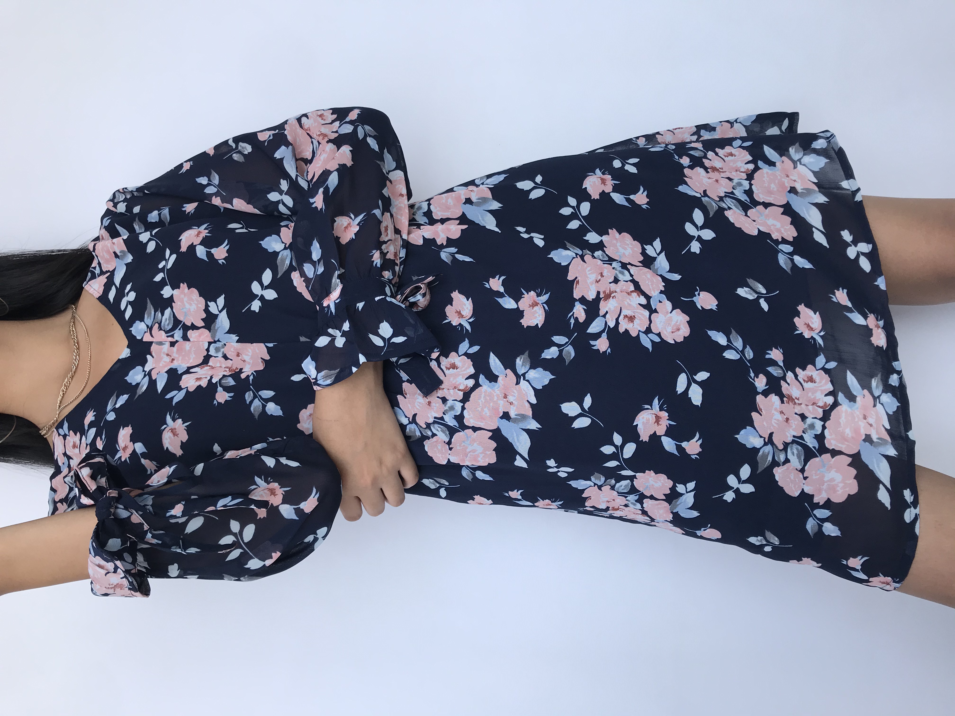Vestido de gasa azul con estampado de flores rosadas, manga larga con volante y lazo para amarrar en el puño, escote ojal y botón posterior, elástico en la cintura y lleva forro
Talla M