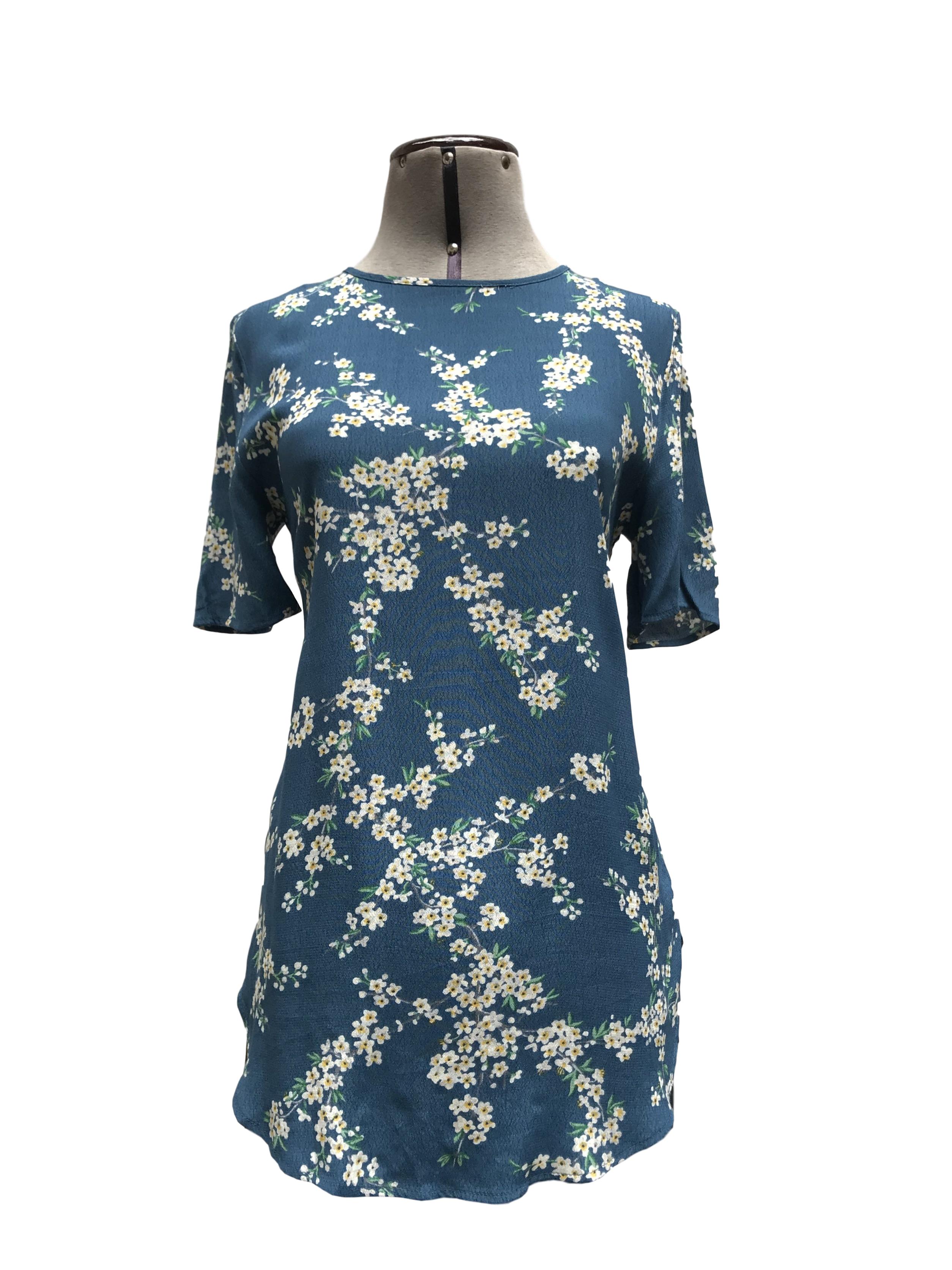 Blusa larga azul con estampado de flores, manga corta, botón posterior en el cuello, bastas redondeadas, es suelta
Talla S