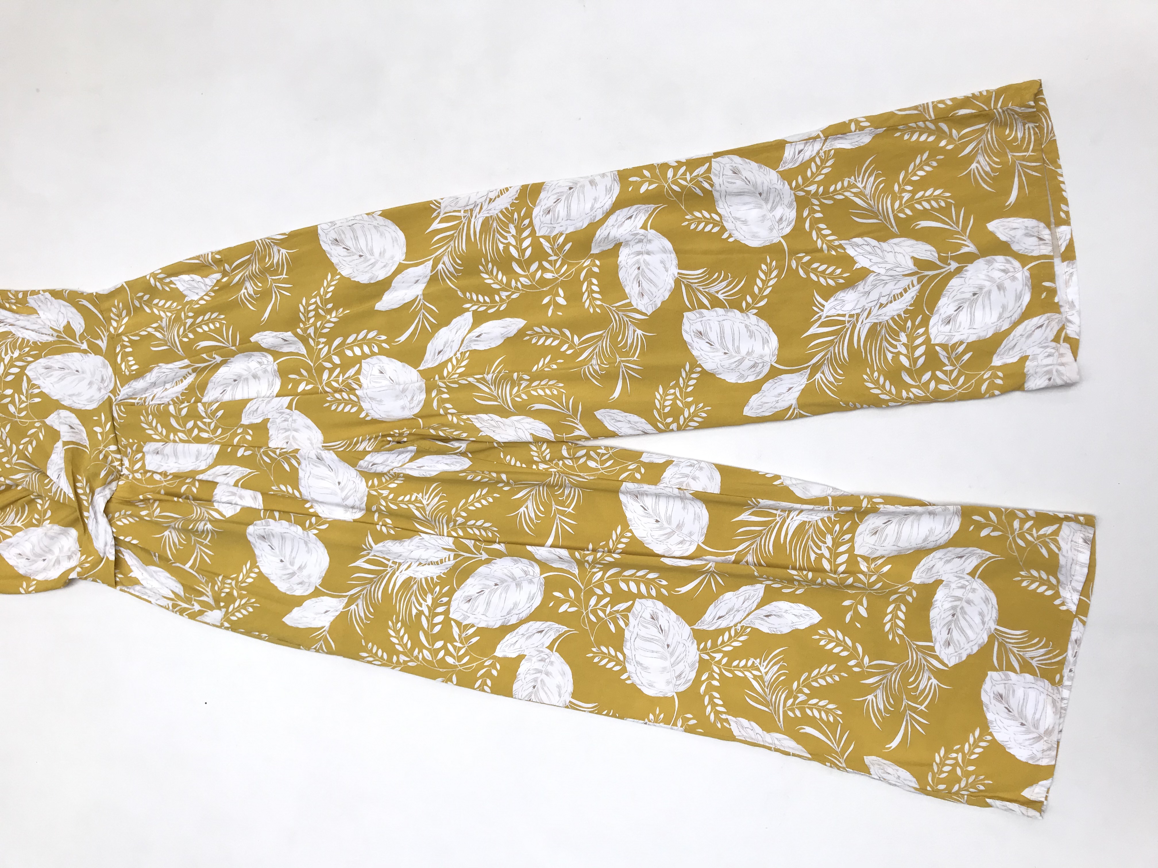 Enterizo Alaniz pantalón amarillo con estampado de hojas blancas, escote cruzado, bolsillos laterales y cierre posterior. Precio original S/ 180