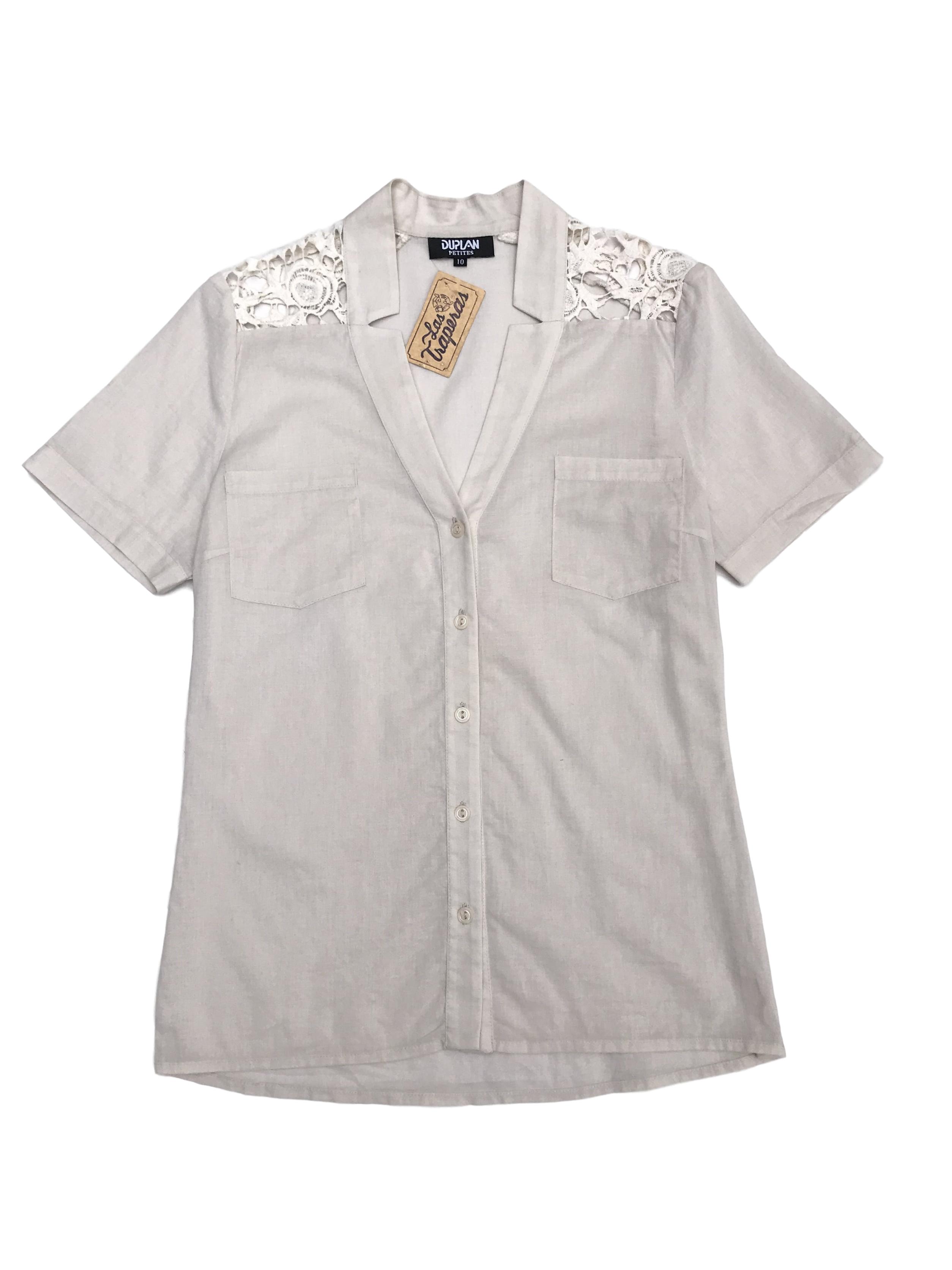 Blusa crema con botones y bolsillos delanteros, encaje en los hombros, tela tipo algodón camisa
