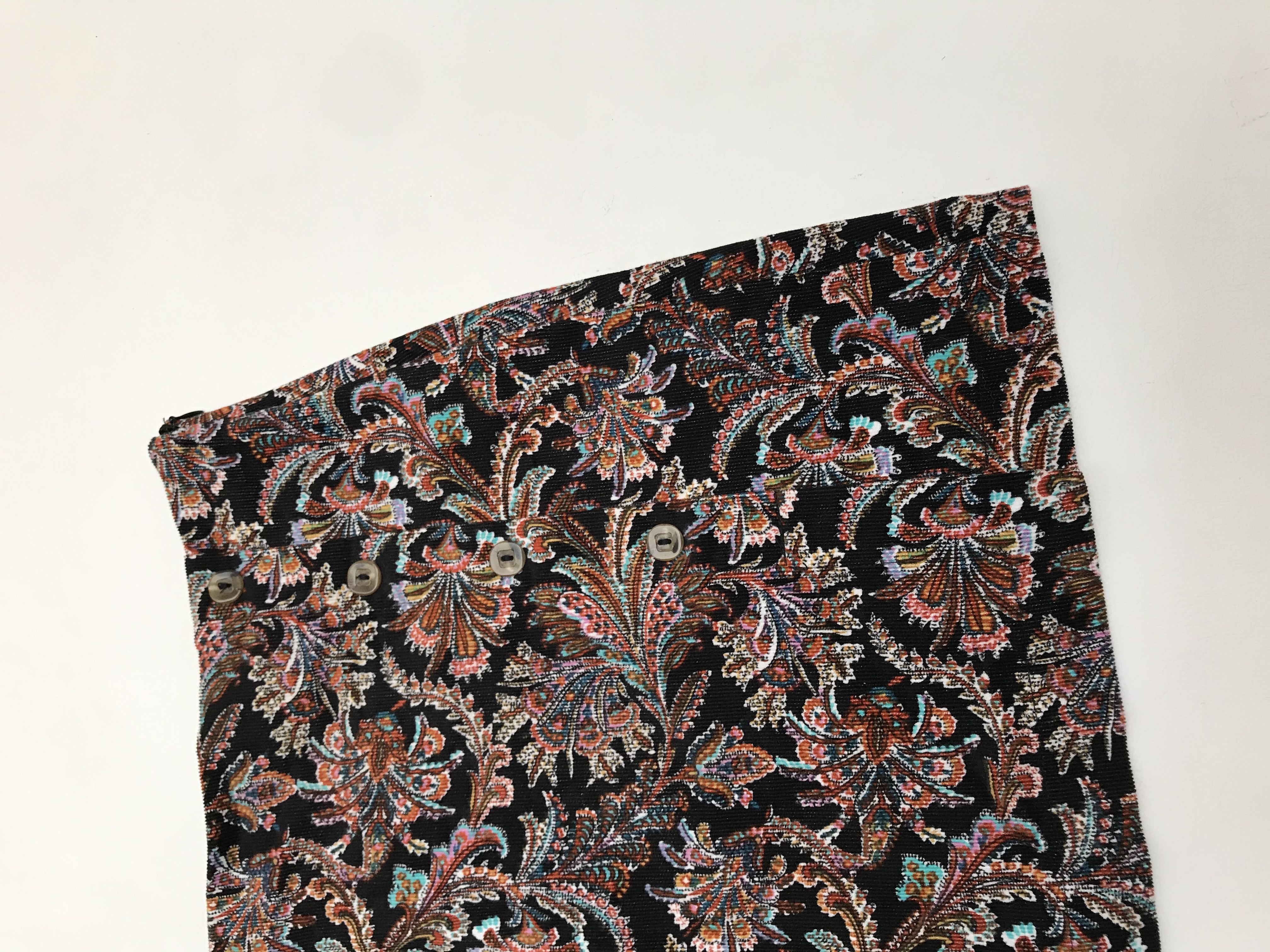 Falda Index de corduroy negro con estampado paisley multicolor, botones y cierre lateral. Pretina 77cm Largo 39cm 