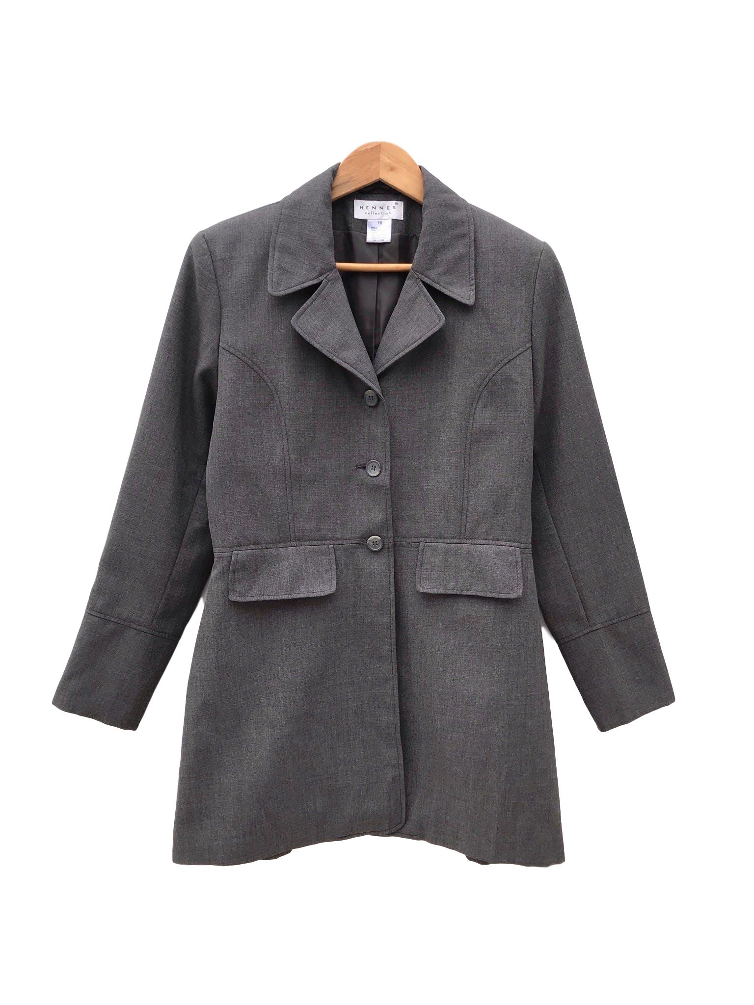 Abrigo gris tela tipo sastre, solapas, botones y bolsillos delanteros, lleva forro y cierre en los puños. Largo 84cm
