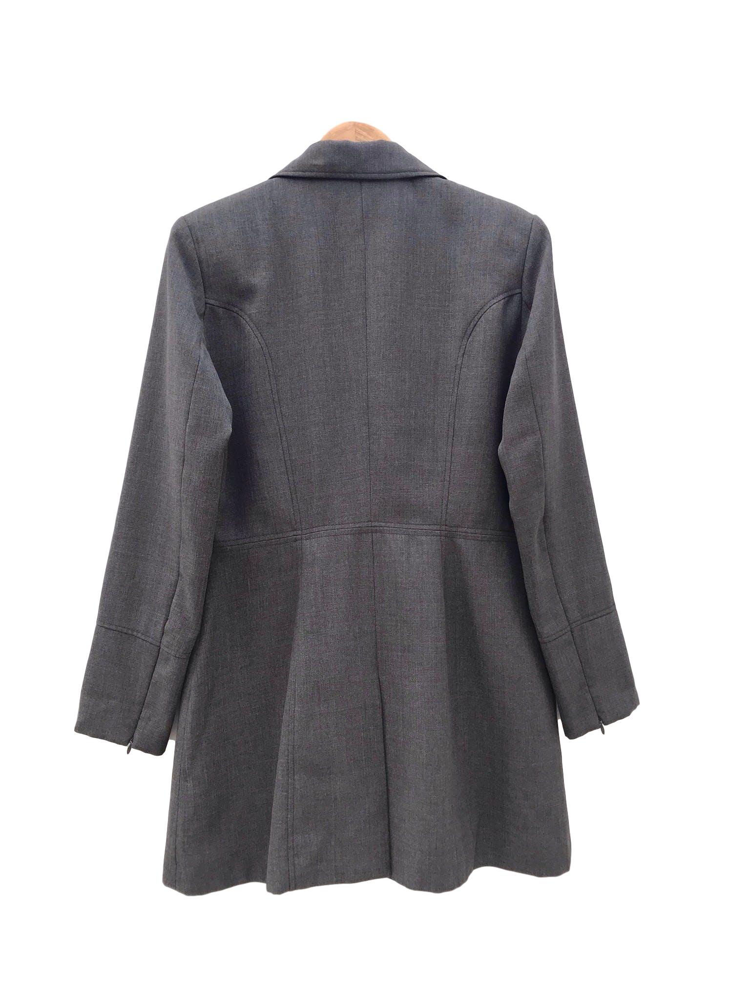 Abrigo gris tela tipo sastre, solapas, botones y bolsillos delanteros, lleva forro y cierre en los puños. Largo 84cm