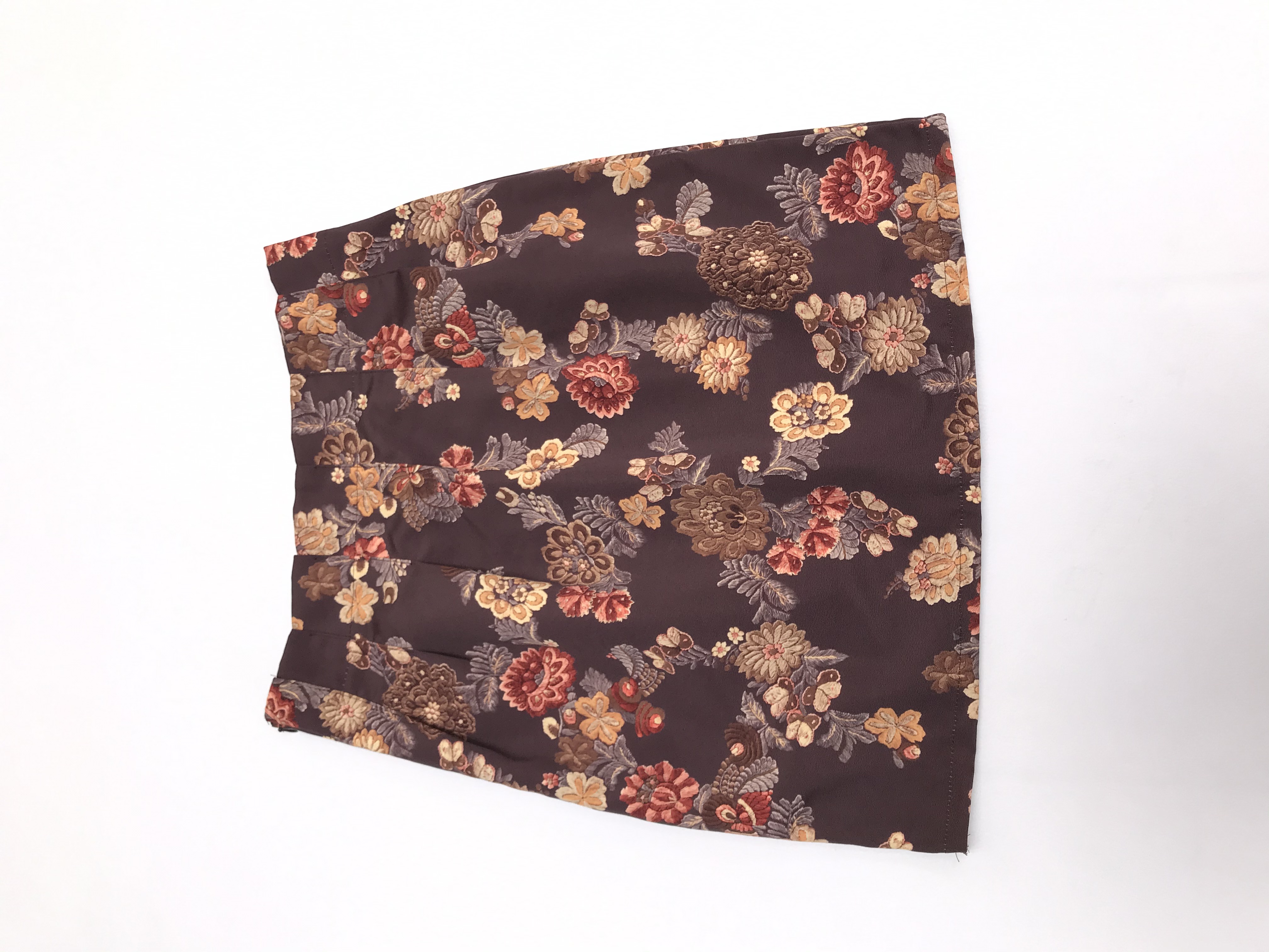 Falda marrón con estampado de flores en tonos tierra, con pliegues y cierre lateral. Pretina 78cm Largo 50cm