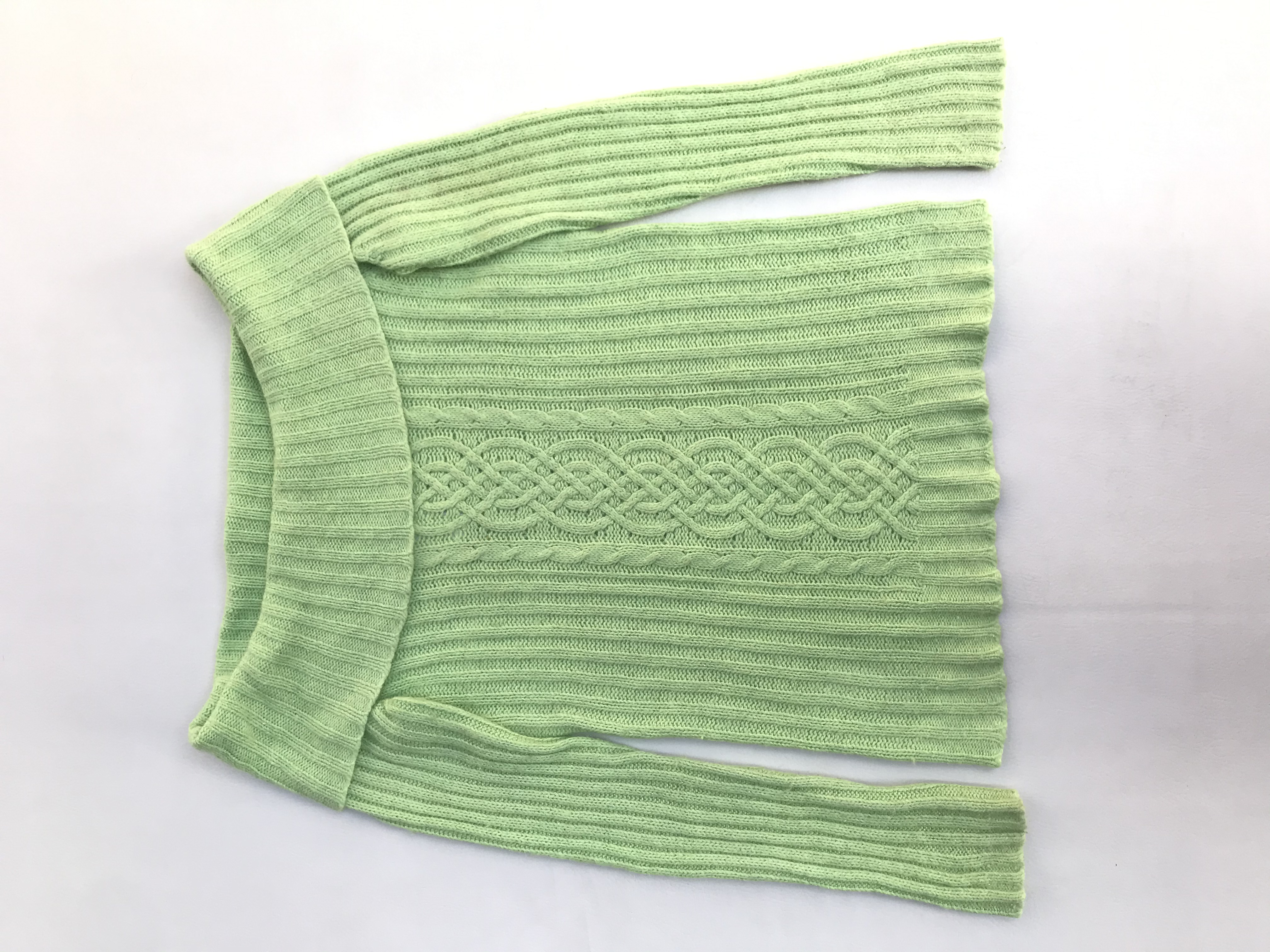 Chompa verde con hilos satinados, cuello bote, textura acanalada y trenzada. Composición ramie, nylon, angora.