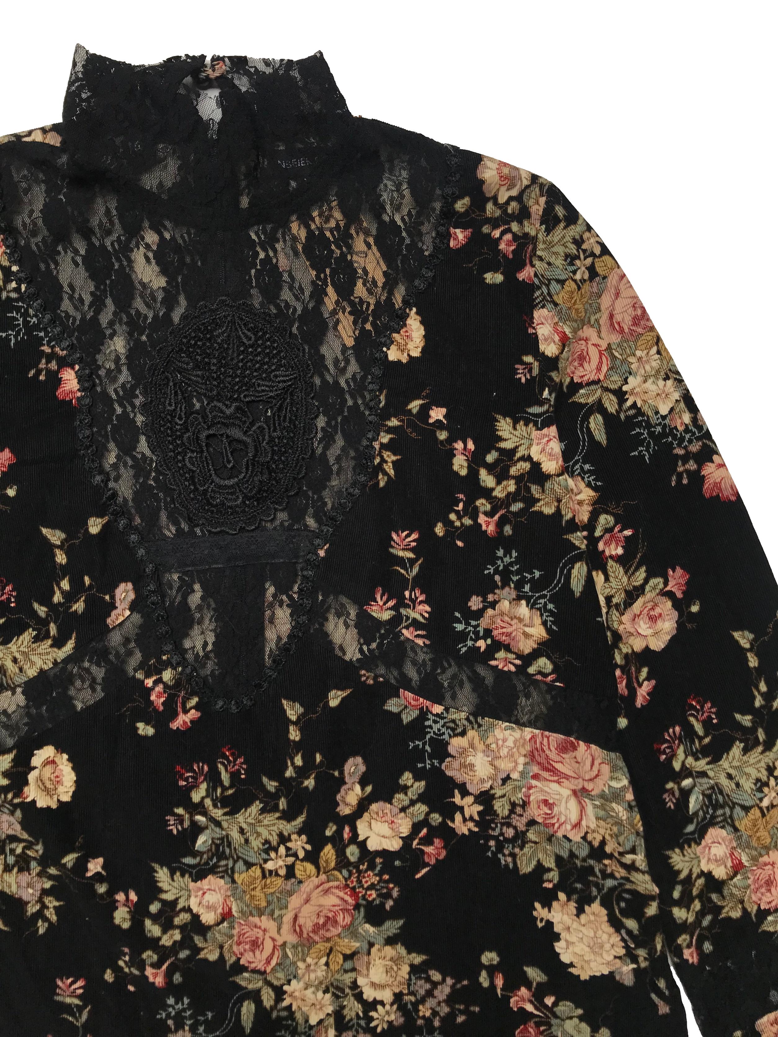 Blusa de pana negra con estampado de flores, detalles de encaje, cuello alto con cierre y botón posteriores, puños con elástico y aberturas laterales en la basta. Busto 100cm Largo 53cm